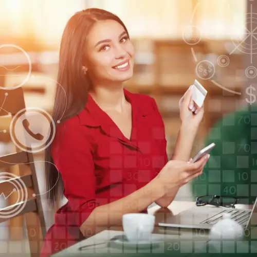 Young professional holding a credit card and smartphone while working on a laptop, representing a successful career in digital marketing and online business growth.